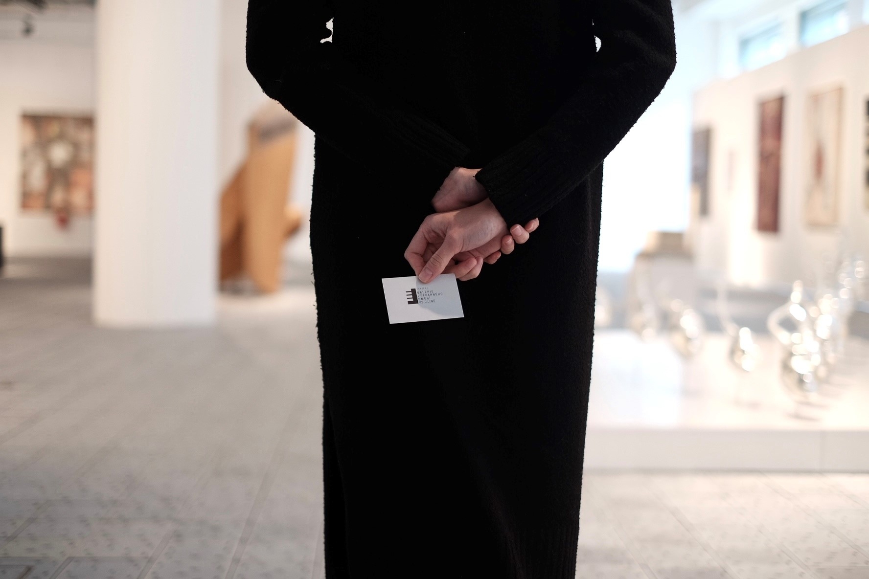 silueta návštěvnice galerie která v ruce drží průkaz Klubu přátel galerie